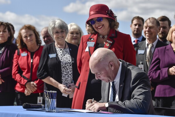 FILE - Republican Gov. Greg Gianforte signs a bill, April 26, 2021, that bans abortions after 20 weeks gestational age as bill sponsor Rep. Lola Sheldon-Galloway, R-Great Falls, looks on in Helena, Mont. A Montana judge ruled on Thursday, Feb. 29, 2024, that Sheldon-Galloway's bill and two others restricting abortion that were passed by the Republican-controlled Legislature in 2021 are unconstitutional. (Thom Bridge/Independent Record via AP, File)