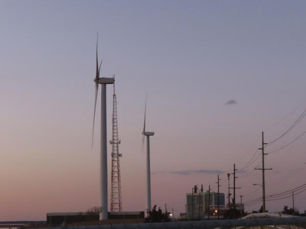 The sun sets behind a land-based wind farm in Atlantic City, N.J. on Feb. 10, 2022. The National Oceanic and Atmospheric Administration on Tuesday, April 4, 2023, issued a report concluding that New Jersey's first planned offshore wind farm, Ocean Wind I, will likely have adverse impacts on whales and other marine animals, but will not seriously harm or kill them. (AP Photo/Wayne Parry)