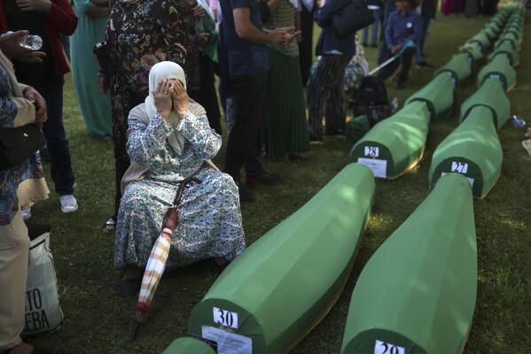 A Bosnian muslim woman, Bahta Aljic mourns next to the coffin containing remains of her husband who is among 50 newly identified victims of Srebrenica Genocide in Potocari, Monday, July 11, 2022. Thousands converge on the eastern Bosnian town of Srebrenica to commemorate the 27th anniversary on Monday of Europe's only acknowledged genocide since World War II. (AP Photo/Armin Durgut)