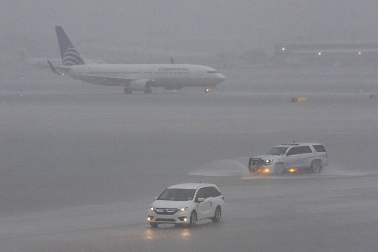 Самолет на взлетно-посадочной полосе после проливного дождя в международном аэропорту Форт-Лодердейл-Голливуд в среду, 12 июня 2024 года, в Форт-Лодердейле, штат Флорида.  Многие рейсы отменены или задержаны из-за плохой погоды.  (AP через Матиаса Дж. Охнера/Miami Herald)