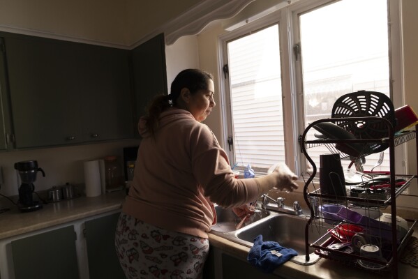 Arelis Ayala washes dishes while making breakfast for her family on Sunday, March 23, 2025, in Rochester, N.Y. (Toni Duncan via AP)