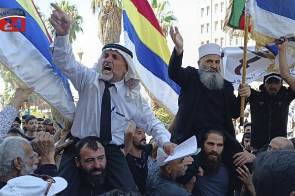 In this photo released on Sunday, Aug. 27, 2023, by Suwayda24, people stage a protest as they wave the Druze flags in the southern city of Sweida, Syria. Anti-government protests have rocked south Syria for the past week. Demonstrators initially took to the streets over surging inflation but are now calling for the ouster of President Bashar Assad, echoing the beginnings of a 2011 uprising that sparked Syria's brutal civil war. (Suwayda24 via AP)