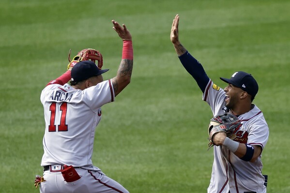 Atlanta Braves left fielder Eddie Rosario, right, and Orlando Arcia (11) celebrate after they defeated the New York Mets in the first baseball game of a doubleheader Saturday, Aug. 12, 2023, in New York. (AP Photo/Adam Hunger)