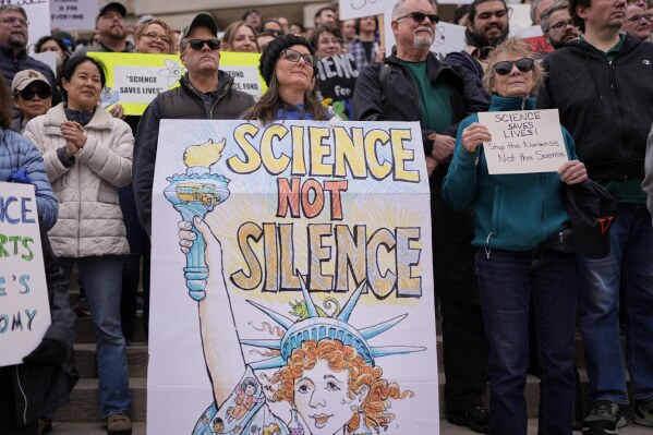 Jennifer Berry, center, wears a sign during a Stand up for Science rally Friday, March 7, 2025, in Nashville, Tenn. (AP Photo/George Walker IV)