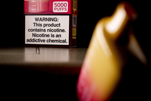 FILE - A health warning is seen on the packaging of a disposable vaping pod device in Washington on Monday, June 26, 2023. Sixty years ago, the U.S. surgeon general released a report that settled a longstanding public debate about the dangers of cigarettes and led to huge changes in smoking in America. Some public health experts say a similar report could help clear the air about vaping.(AP Photo/Andrew Harnik, File)