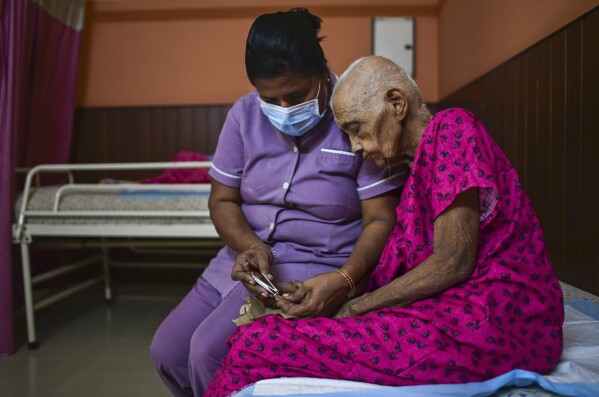Mini, a nurse, trims the nails of Saradammal at the Signature Aged Care in Kochi, Kerala state, India, March 6, 2023. In the last 60 years, the percentage of those aged 60 and over in India's Kerala state has shot up from 5.1% to 16.5% — the highest proportion in any state. This makes Kerala an outlier in a country with a rapidly growing population, soon to be the world's most populous at 1.4 billion. (AP Photo/ R S Iyer)