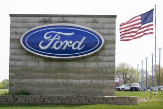 FILE - In this April 27, 2021 file photo, an American flag flies over a Ford auto dealership, in Waukee, Iowa.  Ford’s outlook for the second quarter is improving, as the automaker is seeing strong customer reservations for four of its new vehicles. Ford Motor Co. now anticipates, Thursday, June 17,  its quarterly adjusted earnings before interest and taxes to top its expectations and be significantly better than the year-ago period.  (AP Photo/Charlie Neibergall, File)