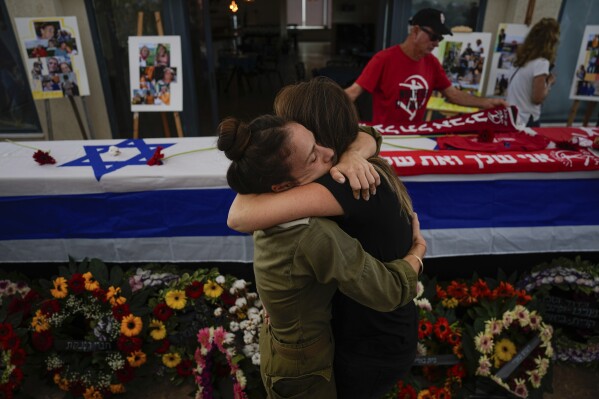 FILE - Mourners embrace during the funeral of Meni and Ayelet Godard, in Kibbutz Palmachim, Israel Sunday, Oct. 29, 2023. (AP Photo/Ariel Schalit, File)