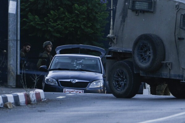 Israeli soldiers stand by a car used by three alleged Palestinian gunmen after they were killed in Nablus, West Bank, on Tuesday, July 25, 2023. Israeli security forces said they opened fire at Palestinian militants who had shot at them from a car, while Palestinian media described the Israeli killing of the gunmen as an ambush following the militants' attempted attack on Israeli forces near a Jewish settlement overlooking Nablus. (AP Photo/Majdi Mohammed)