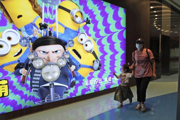 Visitors to a cinema showing the latest "Minions: The Rise of Gru" movie pass by an advertisement for the movie in Beijing, Wednesday, Aug. 24, 2022. The latest “Minions” movie reinforces a message for Chinese audiences that viewers in other countries won’t see: Crime doesn’t pay. (AP Photo/Ng Han Guan)