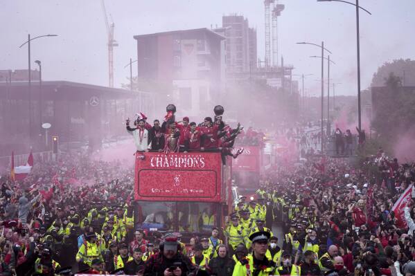 Liverpool players celebrate with the trophy on an open-top bus during the Liverpool FC Premier League victory parade in Liverpool, England, Monday, May 26, 2025.(AP Photo/Jon Super)