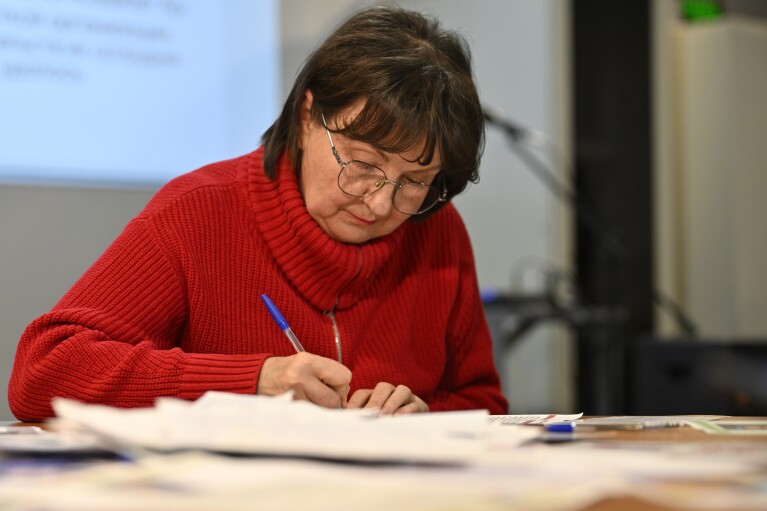 A woman writes a letter to political prisoners in the office of the liberal party Yabloko in Moscow, Russia, on Thursday, Feb. 29, 2024. The party hosts monthly letter-writing evenings across the country. With protests all but stifled, more and more Russians at home and abroad are seeking to help political prisoners by writing them letters. (AP Photo/Dmitry Serebryakov)