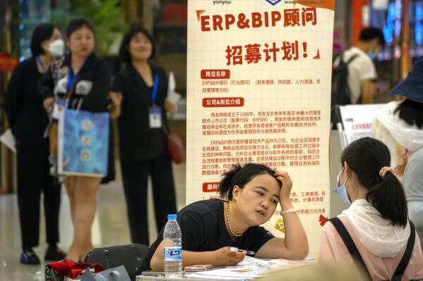 FILE - A recruiter talks with an applicant at a booth at a job fair at a shopping center in Beijing, on June 9, 2023. A record of more than one in five young Chinese are out of work, their career ambitions at least temporarily derailed by a depressed job market as the economy struggles to regain momentum after its long bout with COVID-19. (AP Photo/Mark Schiefelbein, File)