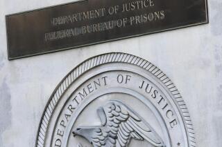 FILE - In this July 6, 2020, file photo a sign for the Department of Justice Federal Bureau of Prisons is displayed at the Metropolitan Detention Center in the Brooklyn borough of New York. While most criminal justice overhauls require action from local officials or legislation, reforming the federal prison system is something President Joe Biden and his Justice Department control. (AP Photo/Mark Lennihan, File)
