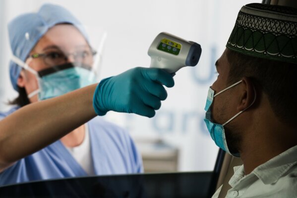 A technician checks a man's temperature before conducting a new coronavirus detection test at a drive-thru testing facility in Abu Dhabi, United Arab Emirates, Thursday, April 2, 2020. Abu Dhabi has begun drive-thru testing for the virus and plans to expand the operation into all of the country's seven sheikhdoms. (AP Photo/Jon Gambrell)