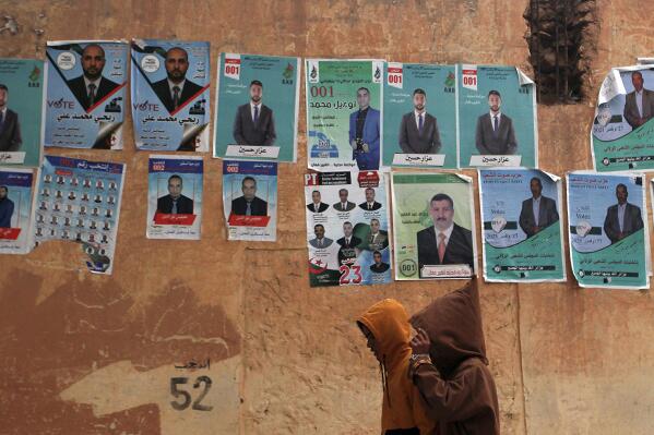 People walk past promotional banners for candidates in the upcoming municipality election in Algiers, Algeria, Thursday, Nov. 25, 2021. (AP Photo/ Fateh Guidoum)