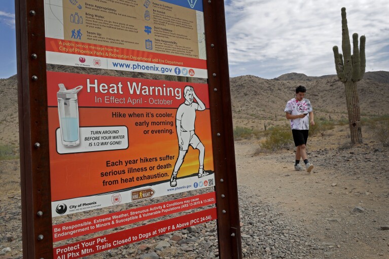 FILE - A hiker finishes his morning walk at the South Mountain Preserve to beat the high temperatures, Thursday, July 11, 2019, in Phoenix. The death of an older Arizona woman when her electricity was cut during a heat spell five years ago spurred changes in shutoff rules. The Arizona agency that oversees regulated utilities now bans power companies from cutting off power for failure to pay during Arizona's hottest months. (AP Photo/Matt York, File)