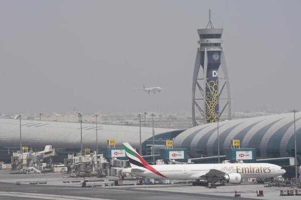 An Emirates Boeing 777 stands at the gate at Dubai International Airport as another prepares to land on the runway in Dubai, United Arab Emirates, Wednesday, Aug. 17, 2022. Dubai International Airport saw a surge in passengers over the first half of 2022 as pandemic restrictions eased and the upcoming FIFA World Cup in Qatar will further boost traffic to the city-state's second airfield, its chief executive said Wednesday. (AP Photo/Jon Gambrell)