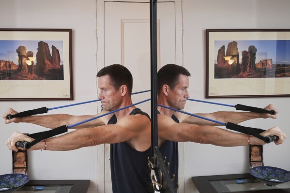 Charles Scott works out with resistance bands at home Thursday, May 1, 2025, in New York. (AP Photo/Frank Franklin II)