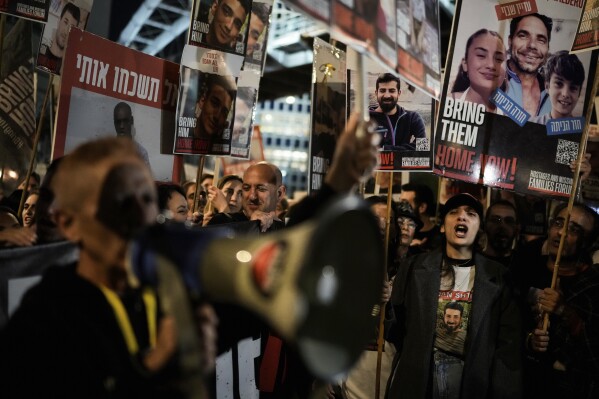 Families and supporters of Israeli hostages held by Hamas in Gaza hold their photos and shout slogans at a rally calling for their return, in Tel Aviv, Israel, Saturday, Dec. 16, 2023. More than 100 Israeli hostages are held in Gaza after being abducted in a Hamas cross-border attack on Oct. 7. (AP Photo/Leo Correa)