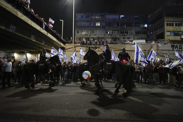 Israeli police officers on horseback disperse demonstrators blocking a highway during a protest against plans by Prime Minister Benjamin Netanyahu's government to overhaul the judicial system in Tel Aviv, Israel, Saturday, March 25, 2023. (AP Photo/Ariel Schalit)