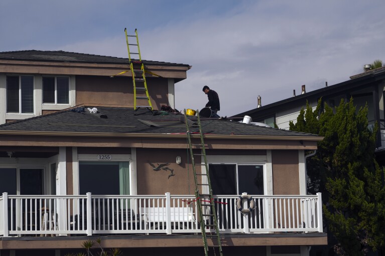 Roofers rush to complete installing roof shingles on a home ahead of incoming storms in Ventura, Calif., Wednesday, Jan. 31, 2024. (AP Photo/Damian Dovarganes)