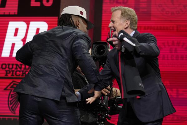 Texas running back Bijan Robinson, left, embraces NFL Commissioner Roger Goodell after being chosen by the Atlanta Falcons with the eighth overall pick during the first round of the NFL football draft, Thursday, April 27, 2023, in Kansas City, Mo. (AP Photo/Jeff Roberson)