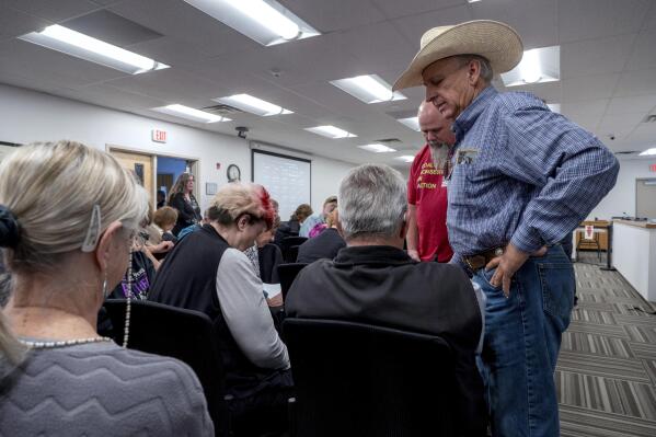 Curt Miller, right, pastor of the East Mountain Cowboy Church in Edgewood, prays with people attending the Town Council meeting, in Edgewood, N.M., Tuesday, April 25, 2023. Residents flocked to a public meeting Tuesday to discuss whether the town should adopt a local abortion-ban ordinance, extending a wave of local abortion restrictions in eastern New Mexico. (Eddie Moore/The Albuquerque Journal via AP)
