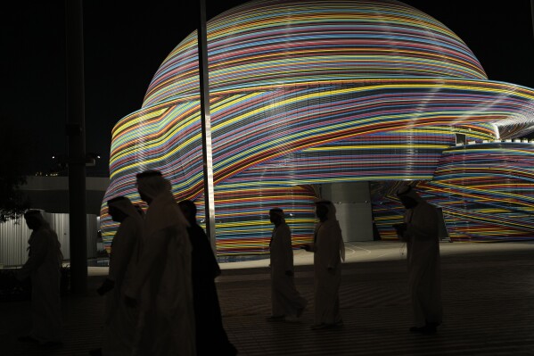 People walk through the COP28 U.N. Climate Summit, Tuesday, Dec. 12, 2023, in Dubai, United Arab Emirates. (AP Photo/Rafiq Maqbool)