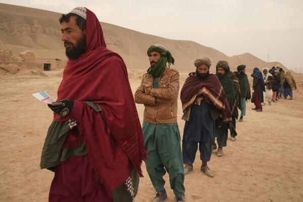 Afghan farmers suffering from consequences of the severe drought line up to receive food rations at a distribution point organised by the IFRC, in Sang-e-Atash, Afghanistan, Monday, Dec. 13, 2021. Severe drought has dramatically worsened the already desperate situation in Afghanistan forcing thousands of people to flee their homes and live in extreme poverty. Experts predict climate change is making such events even more severe and frequent. (AP Photo/Mstyslav Chernov)