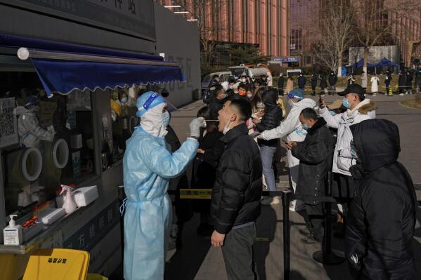 CORRECTS TO SWAB, NOT NASAL SWAB - A People line up to get a swab for the COVID-19 test to meet traveling requirements at a mobile coronavirus testing facility outside a commercial office buildings in Beijing, Sunday, Jan. 16, 2022. Beijing has reported its first local omicron infection, according to state media, weeks before the Winter Olympic Games are due to start. (AP Photo/Andy Wong)