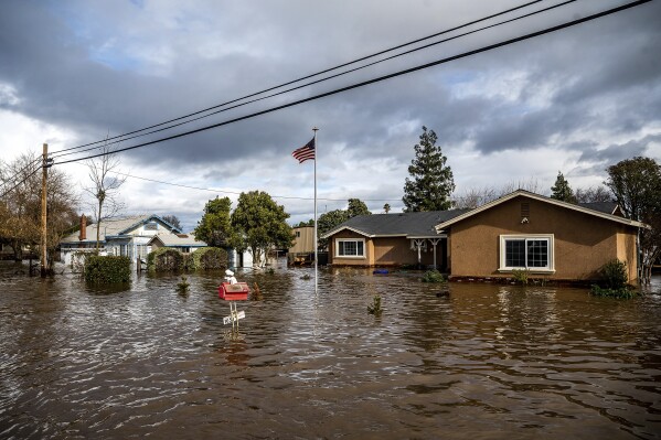 FILE - Floodwaters surround homes on Thornton Road in Merced, Calif., as storms continue battering the state on Jan. 10, 2023. Flood risk and climate change are pushing millions of people to move from their homes, according to a new study by the risk analysis firm First Street Foundation. (AP Photo/Noah Berger, File)