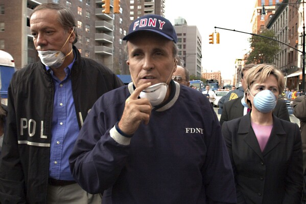 FILE — New York Mayor Rudolph Giuliani, center, leads New York Gov. George Pataki, left, and Sen. Hillary Rodham Clinton, D-N.Y., on a tour of the site of the World Trade Center disaster, Sept. 12, 2001. Giuliani, once warmly regarded as "America's Mayor" in the wake of the 9/11 attacks, and who first rose to prominence as a federal prosecutor going after mobsters with a then-novel approach to racketeering cases, has seen his reputation tumble and his liberty threatened in defense of Donald Trump's bogus election fraud claims. (AP Photo/Robert F. Bukaty, File)