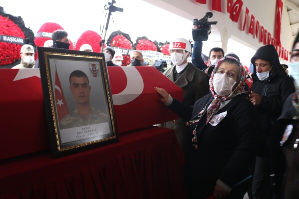 The grandmother of Turkish soldier Adil Kabakli, one of thirteen Turkish soldiers, police and civilians who had been abducted by Kurdish insurgents and found killed in northern Iraq, touches his national flag-draped coffin during the funeral for both Kabakli and fellow soldier Muslum Altintas in Gaziantep, southeastern Turkey, Tuesday, Feb. 16, 2021. (IHA via AP, File)