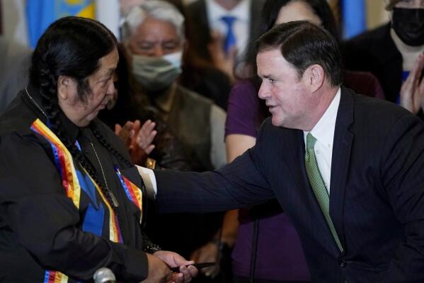 Arizona Republican Gov. Doug Ducey, right, talks with Dr. Damon R. Clarke, left, Chairman of the Hualapai Tribe, after a bill signing allowing a major expansion of sports betting in Arizona at an event at the Heard Museum Thursday, April 15, 2021, in Phoenix. The measure approved by the Legislature adds additional types of table games at tribal casinos and for the first time allows sports betting under licenses issued to tribes and pro sports teams. (AP Photo/Ross D. Franklin)