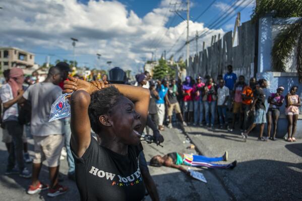 A woman cries near the body of another woman shot dead by the police during a protest demanding the resignation of Prime Minister Ariel Henry in the Delmas area of Port-au-Prince, Haiti, Monday, Oct. 10, 2022. (AP Photo/Odelyn Joseph).