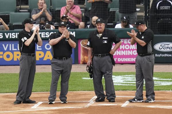 Umpire Joe West, second from right, is applauded by the umpiring crew after a video tribute to West, who is will break the record for most games as a major league umpire with No. 5,376 when he works the Cardinals-White Sox baseball game Tuesday, May 25, 2021, in Chicago. From left are Nic Lentz, Bruce Dreckman, West, and Dan Bellino. (AP Photo/Charles Rex Arbogast)