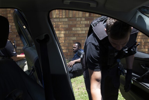 A men, on the ground, suspected of driving a stolen vehicle, is apprehended by private security personal, right, in a suburb east of Johannesburg, South Africa, Friday, Dec. 1, 2023.  (AP Photo/Denis Farrell)