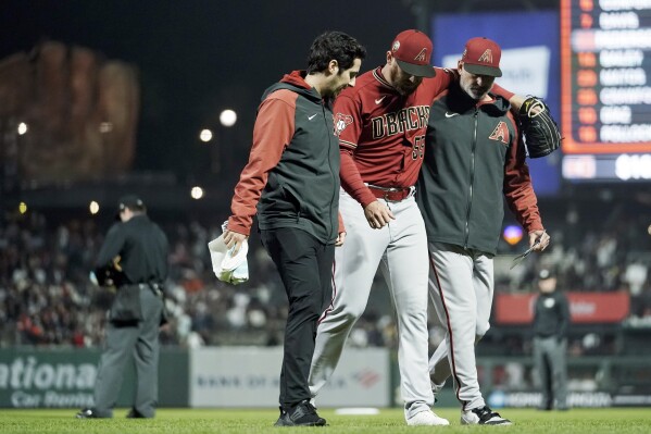 Arizona Diamondbacks pitcher Austin Adams (55) is helped off the field after he was hit by the ball on a single by San Francisco Giants' Joc Pederson during the eighth inning of a baseball game Tuesday, Aug. 1, 2023, in San Francisco. (AP Photo/Godofredo A. Vásquez)