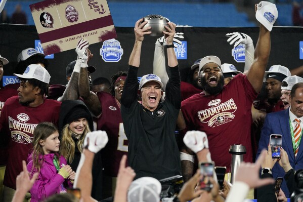 Florida State coach Mike Norvell lifts the trophy after the team's win over Louisville in the Atlantic Coast Conference championship NCAA college football game, Saturday, Dec. 2, 2023, in Charlotte, N.C. (AP Photo/Erik Verduzco)