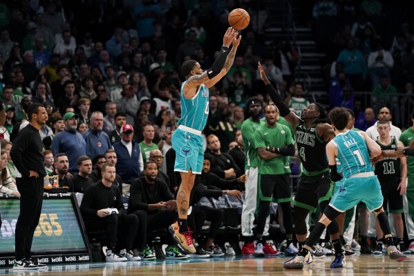 Charlotte Hornets forward Miles Bridges, left, shoots the ball for a score under pressure from Boston Celtics guard Jrue Holiday during overtime in an NBA basketball game, Monday, Nov. 20, 2023, in Charlotte, N.C. (AP Photo/Erik Verduzco)