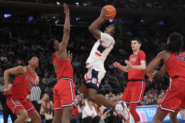 UConn guard Tristen Newton, center, goes to the basket against St. John's guard Nahiem Alleyne (4) during the first half of an NCAA college basketball game in the semifinals of the Big East men's tournament Friday, March 15, 2024, in New York. (AP Photo/Mary Altaffer)