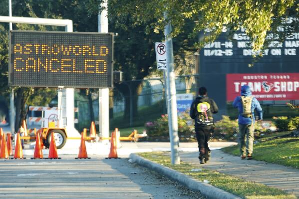 FILE - People walk past a sign announcing Astroworld is canceled outside NRG in Houston on Nov. 6, 2021. The 10 people who lost their lives in a massive crowd surge at the Astroworld music festival in Houston died from compression asphyxia, officials announced Thursday, Dec. 16, 2021. (Elizabeth Conley/Houston Chronicle via AP, File)
