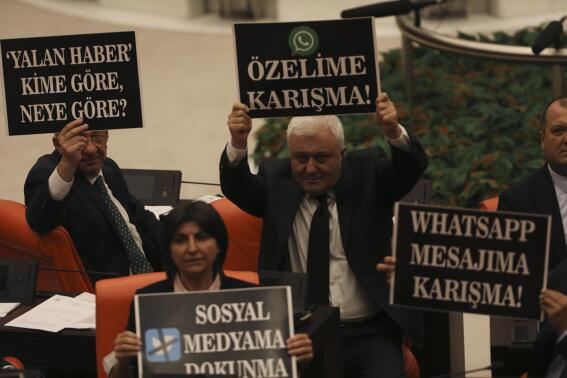 Lawmakers from the main opposition Republican People's Party hold up placards in protest at the parliament, in Ankara, Turkey, Tuesday, Oct. 11, 2022. Turkey's parliament continued to debate a highly controversial draft law Tuesday in Ankara. The government says the bill is aimed at combating fake news and disinformation but critics denounce it as yet another attempt to stifle freedom of expression. (AP Photo/Burhan Ozbilici)