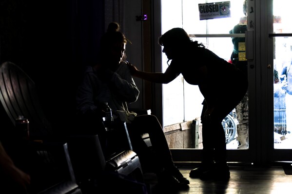 Sarah Laurel, founder of Savage Sisters, checks on a community member at her outreach storefront in the Kensington neighborhood of Philadelphia, Wednesday, May 24, 2023. “Nobody asked for xylazine in the drug supply,” said Sarah Laurel, founder of Savage Sisters, a Philadelphia outreach group. “Before anybody knew it, the community was chemically dependent on it. So now, yes, people do seek it out.” (AP Photo/Matt Rourke)