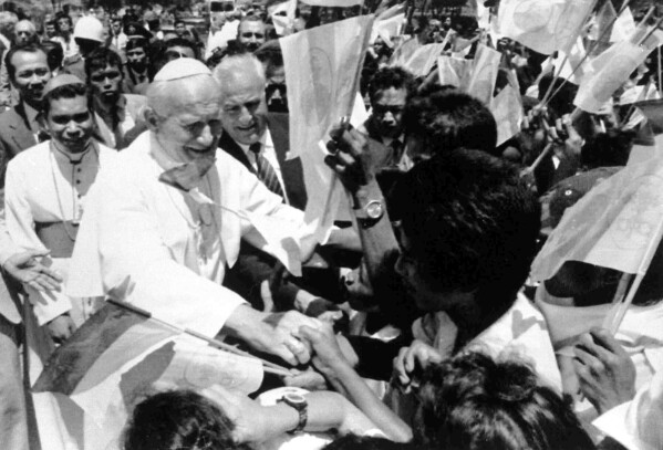 Pope John Paul II shakes hands with flag-waving local students upon his arrival in Dili, East Timor, Oct. 12, 1989. (AP Photo/Staff/Marquez) 
