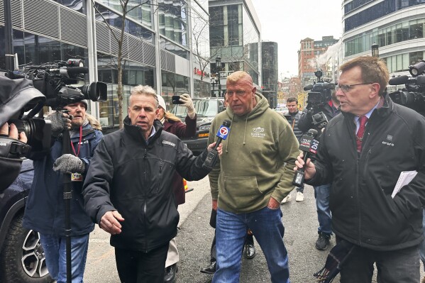 Massachusetts State Police Sgt. Gary Cederquist, center, leaves federal court. Tuesday, Jan 30, 2024, in Boston. Cederquist, 58, of Stoughton, and five others have been charged Tuesday in a scheme to allegedly take bribes including a new snowblower and driveway in exchange for giving passing scores on commercial driving tests, the U.S. attorney’s office said Tuesday. (AP Photo/Michael Casey)