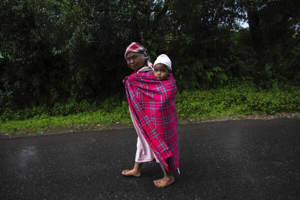 A woman carries a child near the Swer sacred forest in East Khasi Hills region of Meghalaya near Cherrapunji, India, Thursday, Sept. 7, 2023. (AP Photo/Anupam Nath)