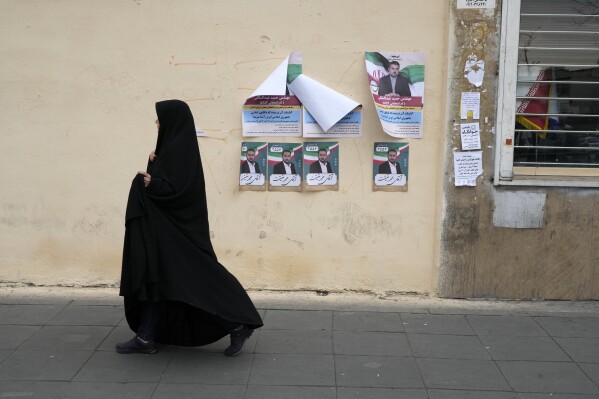 A woman walks past electoral posters of candidates for the March 1, parliamentary election, in downtown Tehran, Iran, Thursday, Feb. 22, 2024. Candidates for Iran's parliament began campaigning Thursday in the country's first election since the bloody crackdown on the 2022 nationwide protests that followed the death of 22-year-old Mahsa Amini in police custody. (AP Photo/Vahid Salemi)