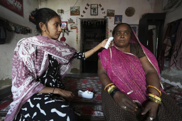 Field data collector Manisha Parmar, left, checks the temperature of Shantaben Vanzara in Ahmedabad, India, Wednesday, April 2, 2025. (AP Photo/Ajit Solanki)